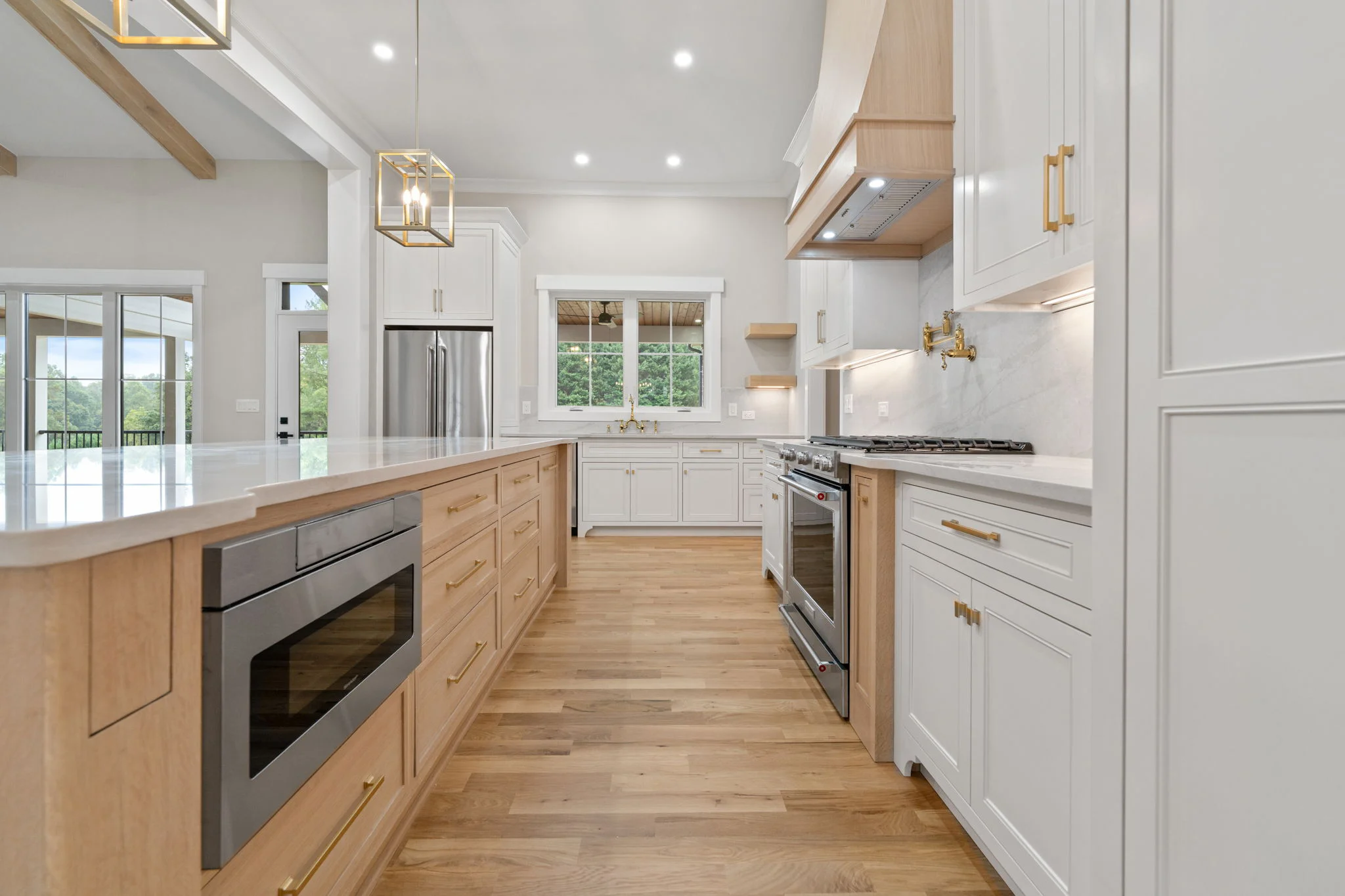 Luxury kitchen interior real estate photo in Lewisville NC featuring white shaker cabinets, natural wood island, gold hardware, quartz countertops, and stainless appliances