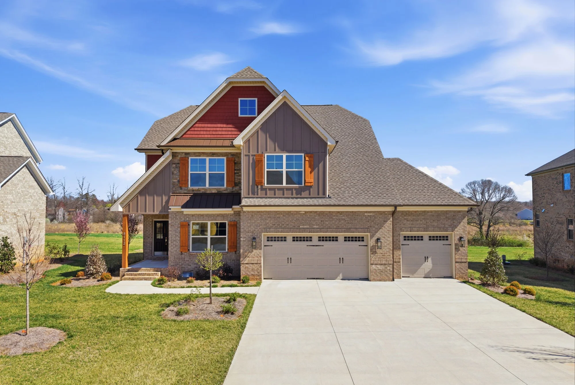 Aerial exterior view of craftsman-style home in Stokesdale NC featuring 3-car garage, board and batten siding, stone accents, and orange shutters