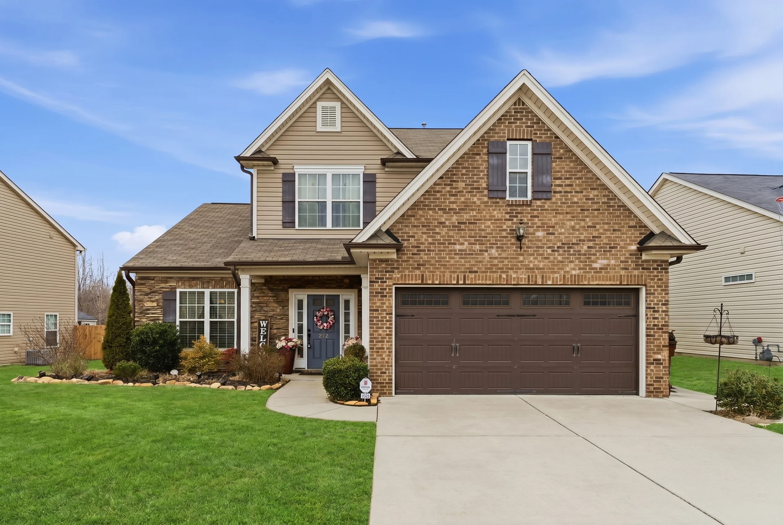 Exterior real estate photo of brick two-story home in Thomasville NC with 2-car garage, stone accents, and manicured lawn